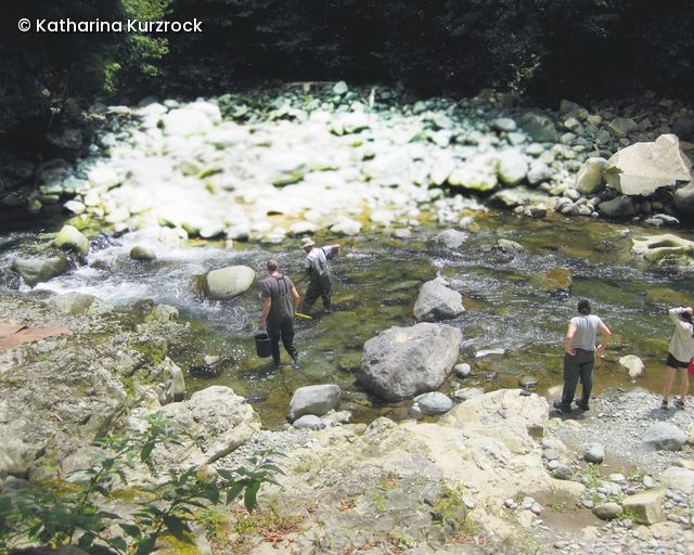 Zwei Forscher stehen in einem Bauchlauf in Regenkleidung