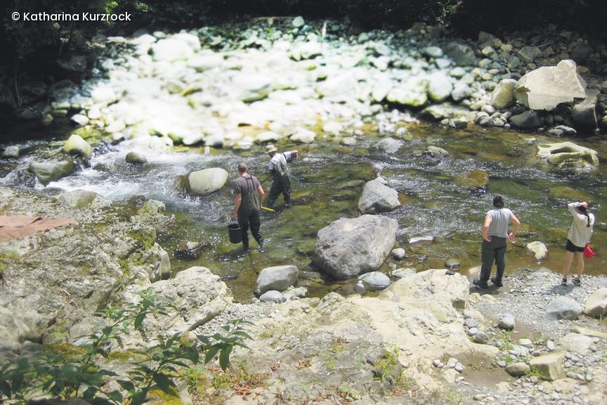 Zwei Forscher stehen in einem Bauchlauf in Regenkleidung